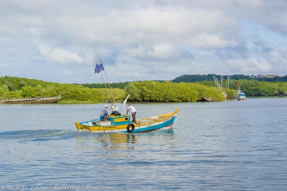 Imagem de pescadores com seu barco no mar.